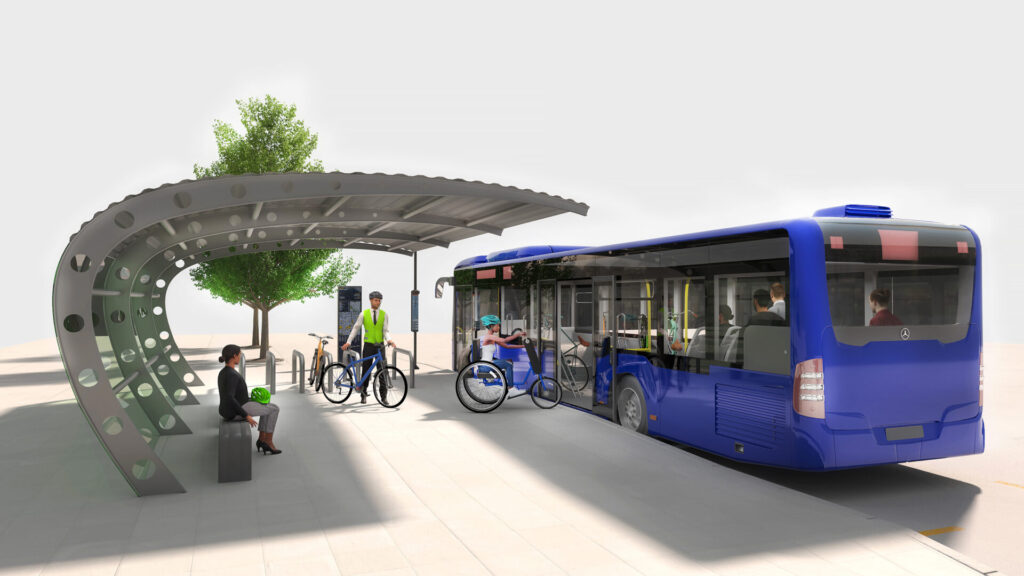 A rendering of a bus stop with a futuristic-looking bus shelter, next to a single decker bus with bicycle racks on it and middle doors. Someone on a hand cycle is negotiating the entrance (although it's not clear how she'll be able to turn around once inside.) A commuter type wearing a tie, hi-vis jacket, and helmet, waits to load his bicycle on behind her. A woman sits on the bench holding a helmet, presumably waiting for other people to get onto the bus.
